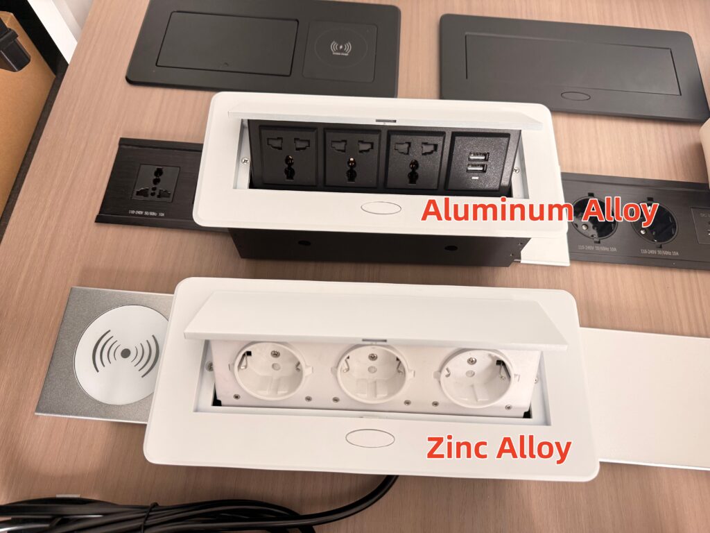 Comparison of aluminum alloy and zinc alloy pop-up desktop socket panels showing finish and material differences